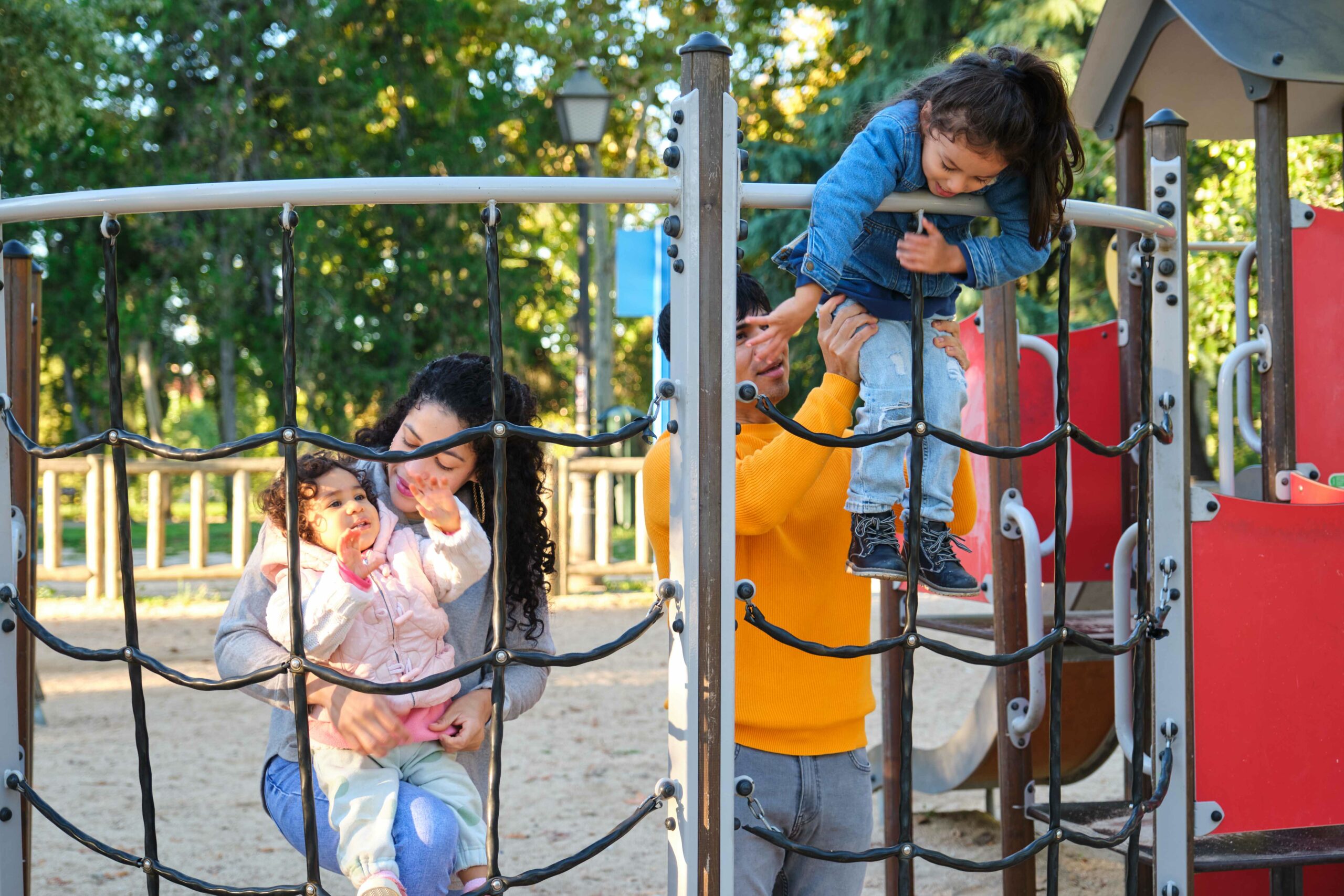 latin family with two children playing climbing in a playground.