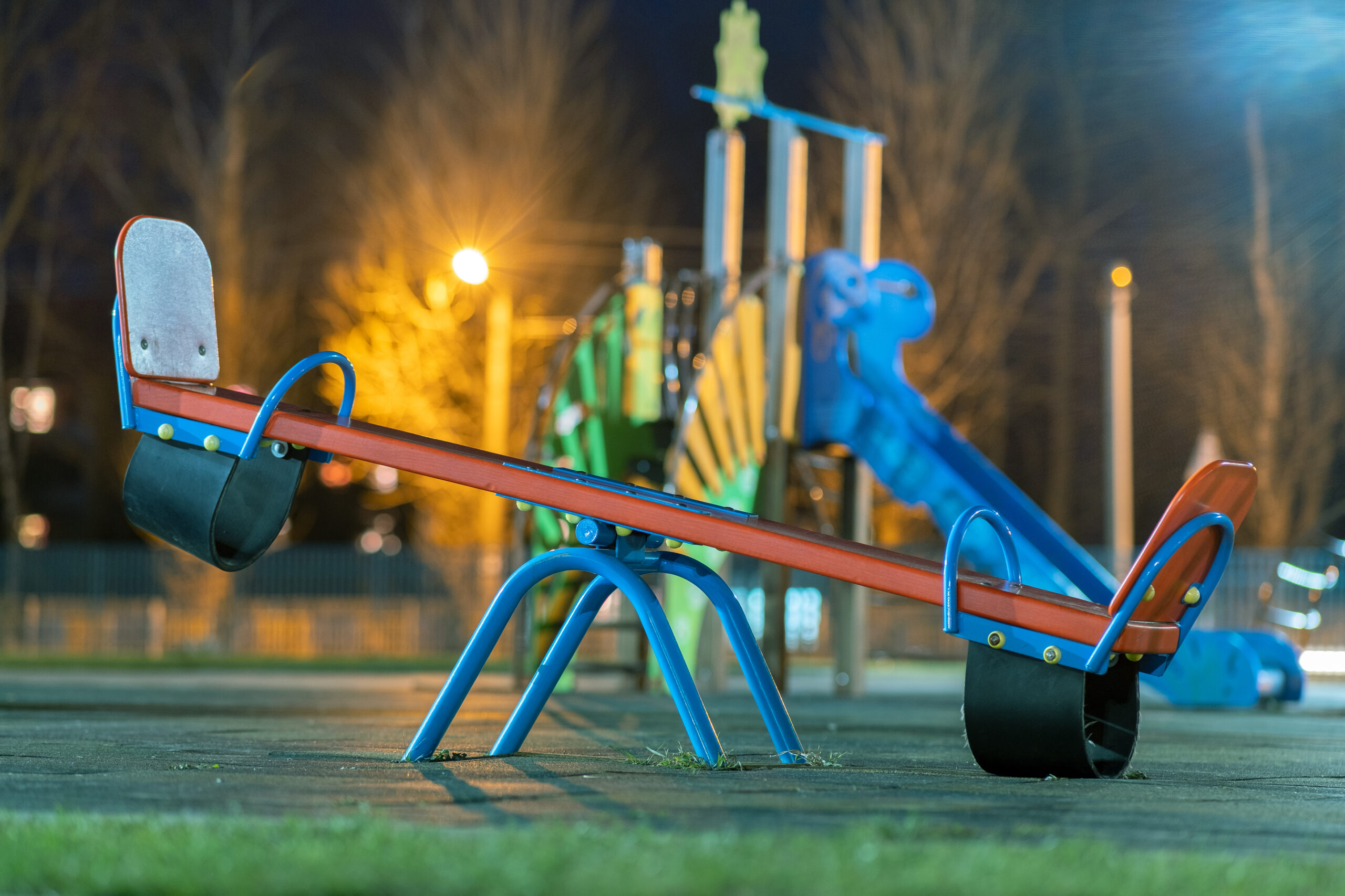 seesaw swing in preschool yard with soft rubber flooring at night.
