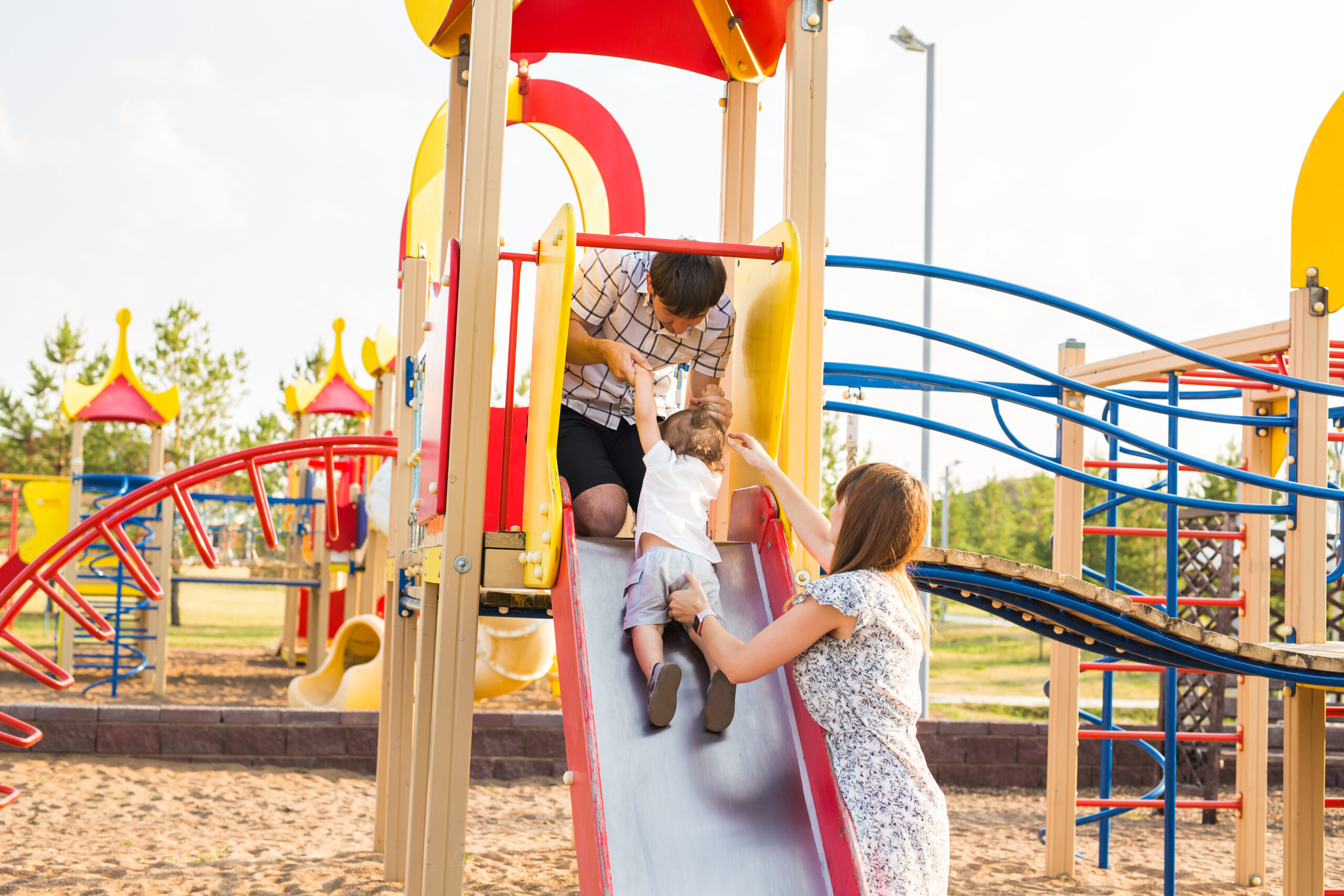 the little boy happy outdoors in playground with his parents